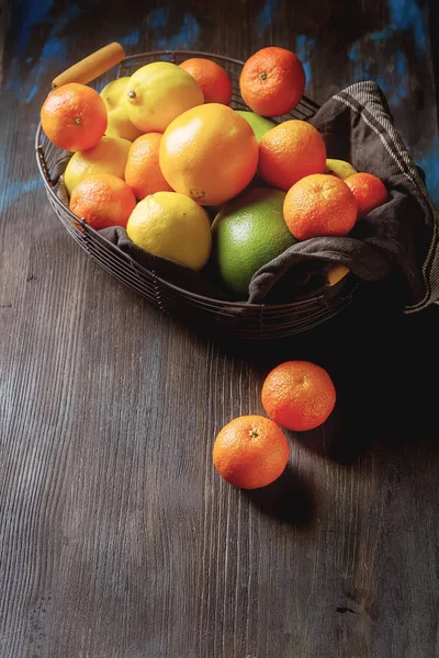 Différents agrumes frais dans un panier sur un fond en bois . — Photo