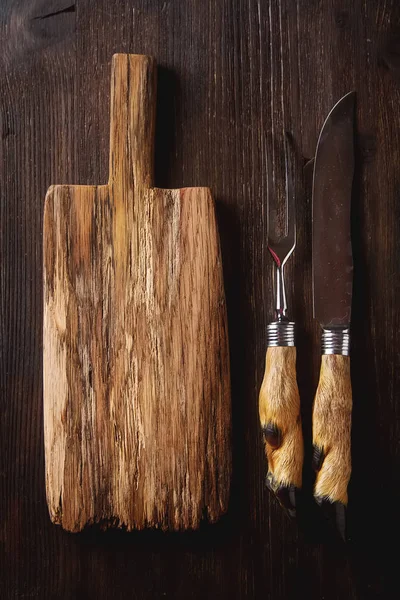 Planche à découper, avec fourchette et couteau sculptés sur fond sombre — Photo