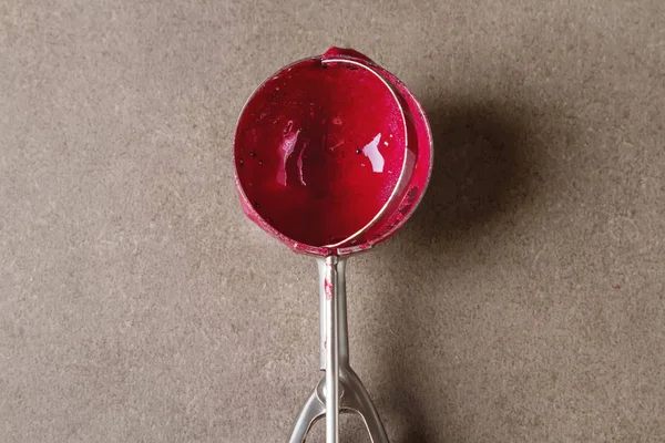 Cuchara de helado con sorbete rojo se encuentra en una mesa gris. Espacio para —  Fotos de Stock