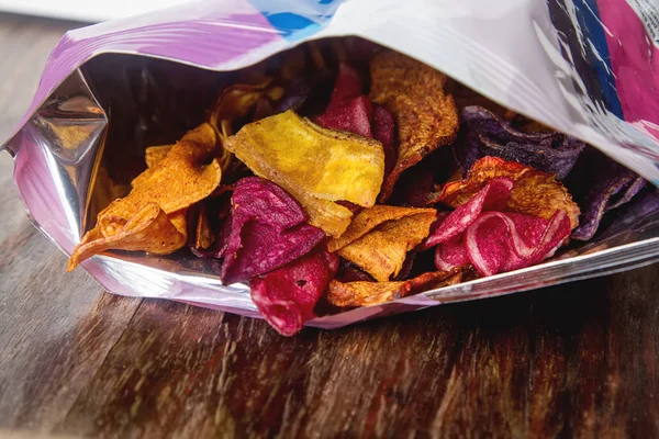 Beet and carrot salty chips in the bag from the store. Wooden da