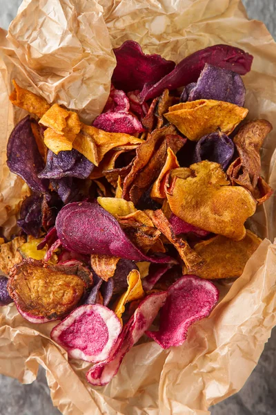 Beet and carrot salty chips on baking paper in an old brown wick — Stock Photo, Image