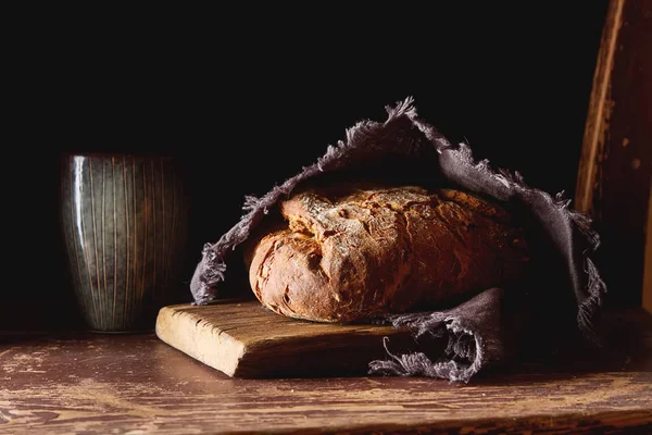 Świeży domowy chleb czarny francuski. Ciemne tło. — Zdjęcie stockowe