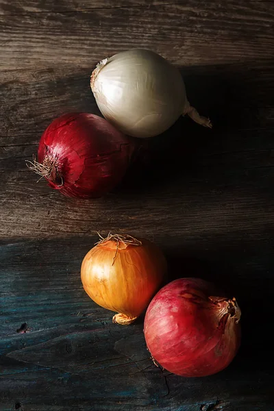 Cebolas de diferentes variedades e cores. Fundo cinza escuro . — Fotografia de Stock