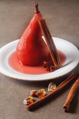 Kırmızı şarap, beyaz bir plaka üzerinde yıldız anason ile armut haşlanmış. Dar