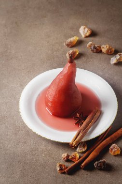 Kırmızı şarap, beyaz bir plaka üzerinde yıldız anason ile armut haşlanmış. Dar