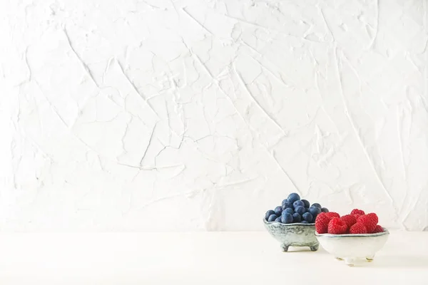 บลูเบอร์รี่สุกและราสเบอร์รี่ในชามแสง สีขาว backg — ภาพถ่ายสต็อก