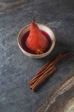 Kırmızı şarap, beyaz bir plaka üzerinde yıldız anason ile armut haşlanmış. Dar