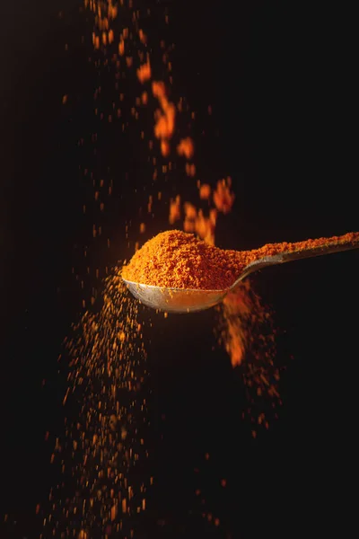 Metall sked med torkade röda paprikor. Fallande kryddor. Svart bakgr — Stockfoto