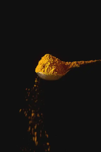 Metalen lepel met gele kurkuma. Dalende specerijen. Zwarte CHTERGRO — Stockfoto