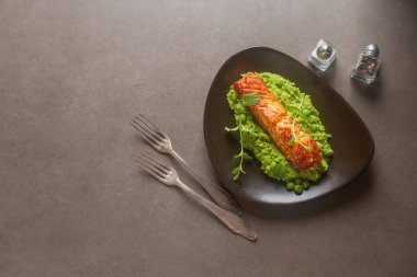 Izgara somon bezelye püresi kahverengi bir plaka üzerinde nane ile dekore edilmiştir. G