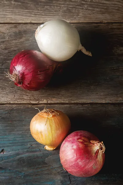 Cebolas de diferentes variedades e cores. Fundo cinza escuro . — Fotografia de Stock