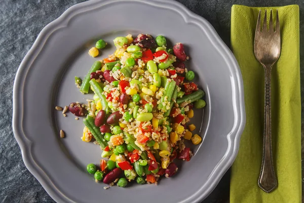 Fresh quinoa salad with peas, beans and peppers. Gray background