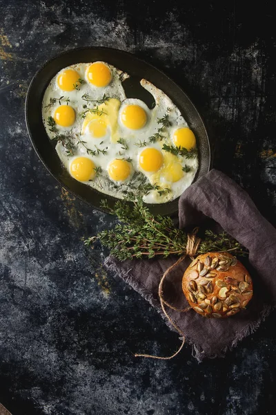 Huevos fritos de codorniz en una sartén con tomillo. Fondo oscuro . — Foto de Stock