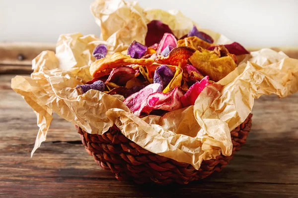 Beet and carrot salty chips on baking paper in an old brown wick — Stock Photo, Image