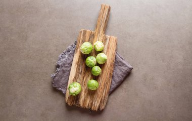 Bir ahşap tahta üzerinde taze Brüksel lahanası. Koyu gri arka plan.