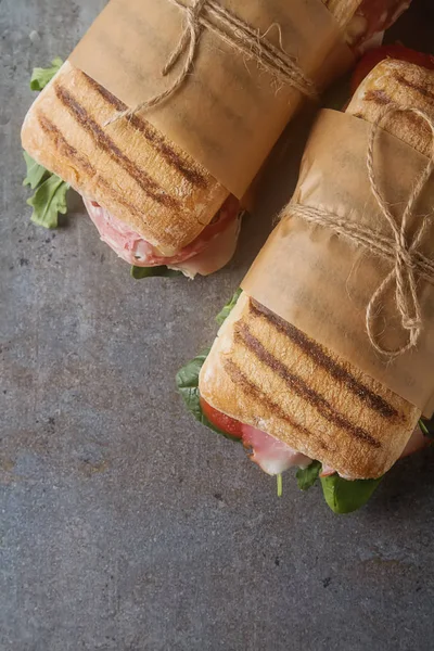 Baguete francesa com salsicha, tomate e alface. Backgro escuro — Fotografia de Stock