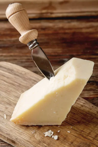 Stuk van Italiaanse Parmezaanse kaas met een mes. Donker hout backgro — Stockfoto