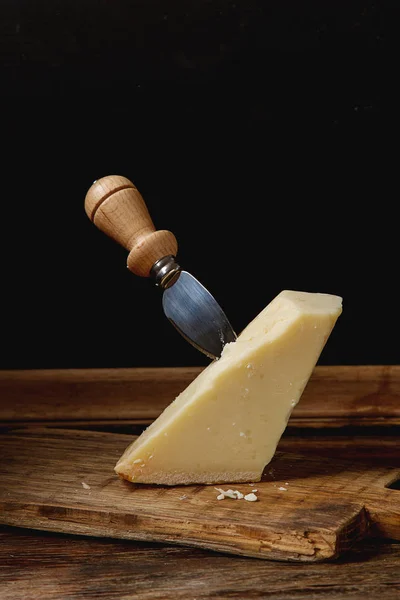 Pedaço de queijo parmesão italiano com uma faca. Backgro de madeira escura — Fotografia de Stock