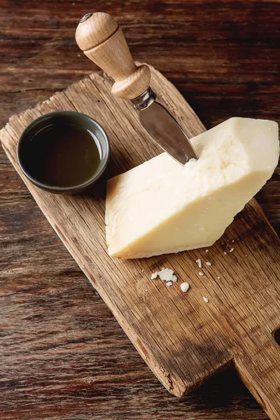 Pedaço de queijo parmesão italiano com uma faca. Backgro de madeira escura — Fotografia de Stock