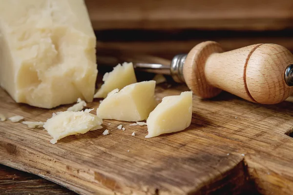 Pedaço de queijo parmesão italiano com uma faca. Backgro de madeira escura — Fotografia de Stock