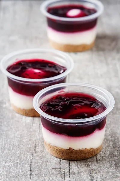 Ready berry cheesecake in a plastic pot. Dark gray wooden backgr — Stock Photo, Image