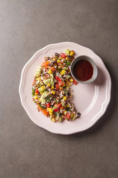 Quinoa salad with corn, tomatoes, avocado, pink sauce on a plate