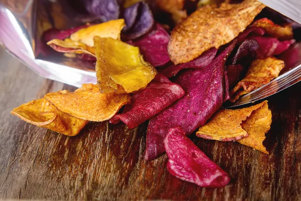 Beet and carrot salty chips in the bag from the store. Wooden da — Stock Photo, Image