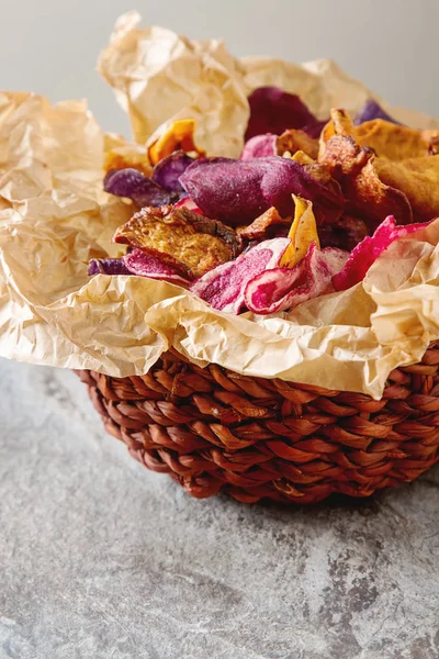 Beet and carrot salty chips on baking paper in an old brown wick — Stock Photo, Image