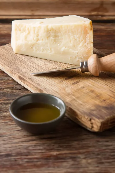 Кусочек итальянского сыра пармезан с ножом. Тёмный древолаз — стоковое фото