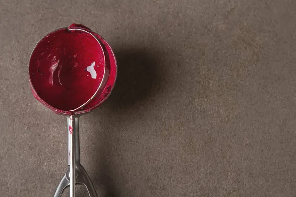 Kaşık dondurma kırmızı sorbe ile gri bir masada yatıyor. Alan — Stok fotoğraf
