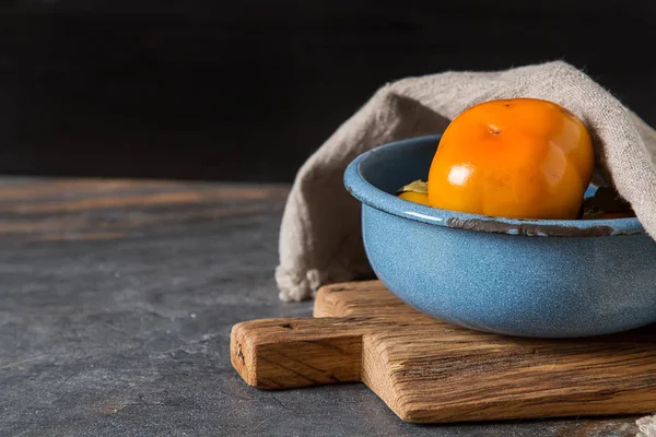 Cáqui de laranja maduro em uma tigela azul em uma bandeja de madeira. Dieta, ou — Fotografia de Stock