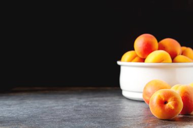 Olgun kayısı bir kase. Koyu arka plan. Bir vegan yemek ve bir