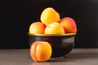 Olgun kayısı bir kase. Koyu arka plan. Bir vegan yemek ve bir