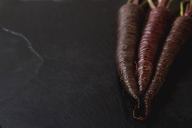 Olgun siyah havuç. Koyu taş arka plan. Sonbaharda hasat. En iyi v