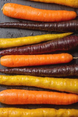  Olgun siyah, turuncu ve sarı havuç. Koyu taş arka plan. A