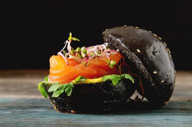 Somon Balık, marul, hardal ile siyah burger. Koyu arka plan