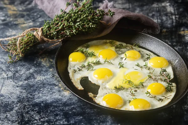 Huevos fritos de codorniz en una sartén con tomillo. Fondo oscuro . — Foto de Stock