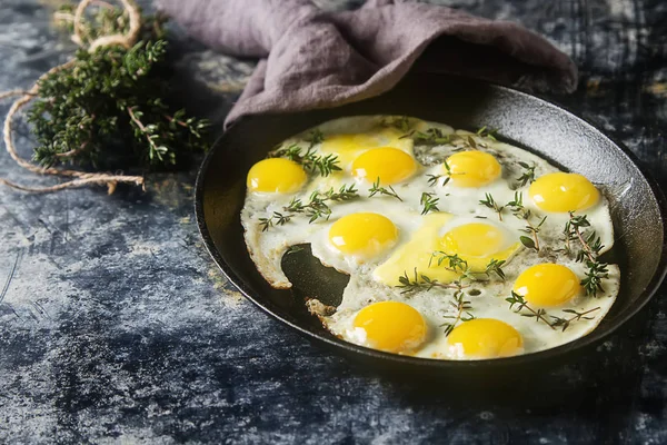 Huevos fritos de codorniz en una sartén con tomillo. Fondo oscuro . — Foto de Stock