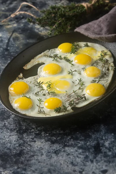 Huevos fritos de codorniz en una sartén con tomillo. Fondo oscuro . — Foto de Stock