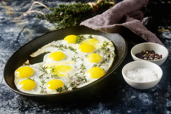 Huevos fritos de codorniz en una sartén con tomillo. Fondo oscuro . — Foto de Stock