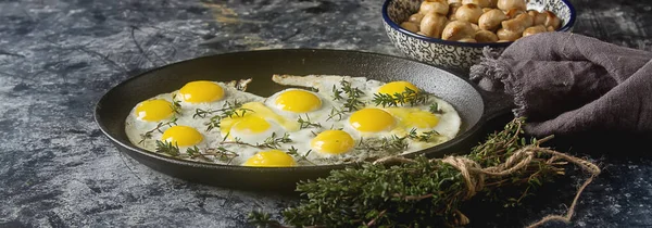 Huevos de codorniz fritos en una sartén con tomillo y champiñones. Oscuro — Foto de Stock