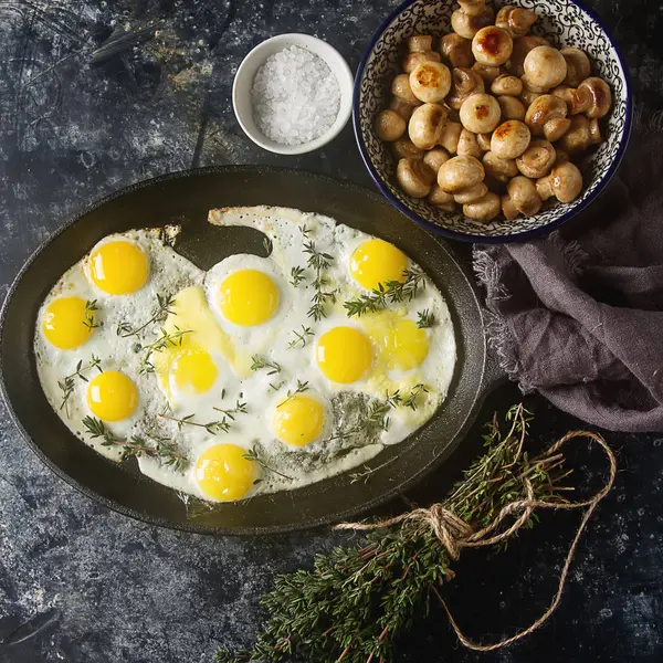 Huevos de codorniz fritos en una sartén con tomillo y champiñones. Oscuro — Foto de Stock