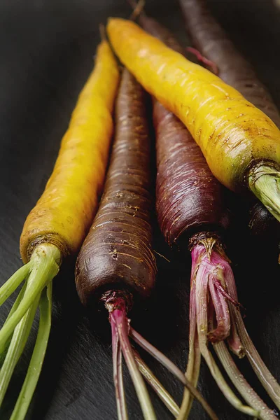 Rijpe zwarte en gele wortelen. Donkere stenen achtergrond. Herfst har — Stockfoto