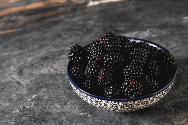 BlackBerry bir seramik tabak içinde. Koyu arka plan. Tatlı berry.