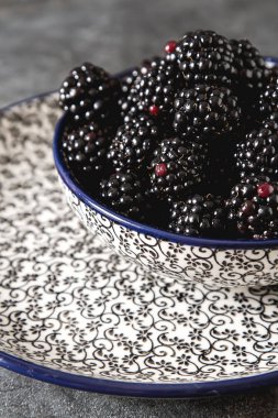 BlackBerry bir seramik tabak içinde. Koyu arka plan. Tatlı berry.