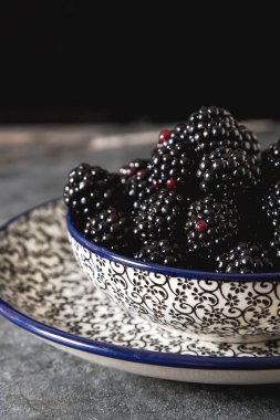 BlackBerry bir seramik tabak içinde. Koyu arka plan. Tatlı berry.