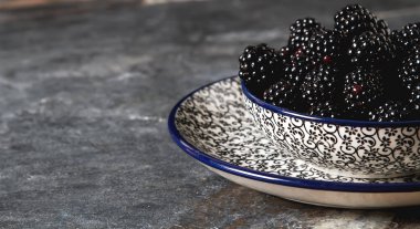 BlackBerry bir seramik tabak içinde. Koyu arka plan. Tatlı berry.