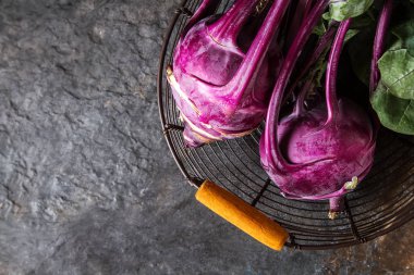 Yeşil yaprakları ile olgun mor şalgam. Gri taş arka plan.