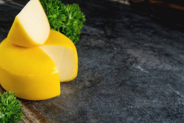 Yuvarlak gouda peyniri maydanoz ile. Koyu arka plan.