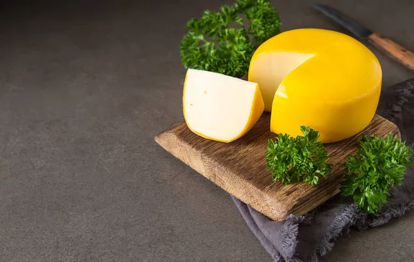 Ronde Goudse kaas met peterselie. Donkere achtergrond. — Stockfoto